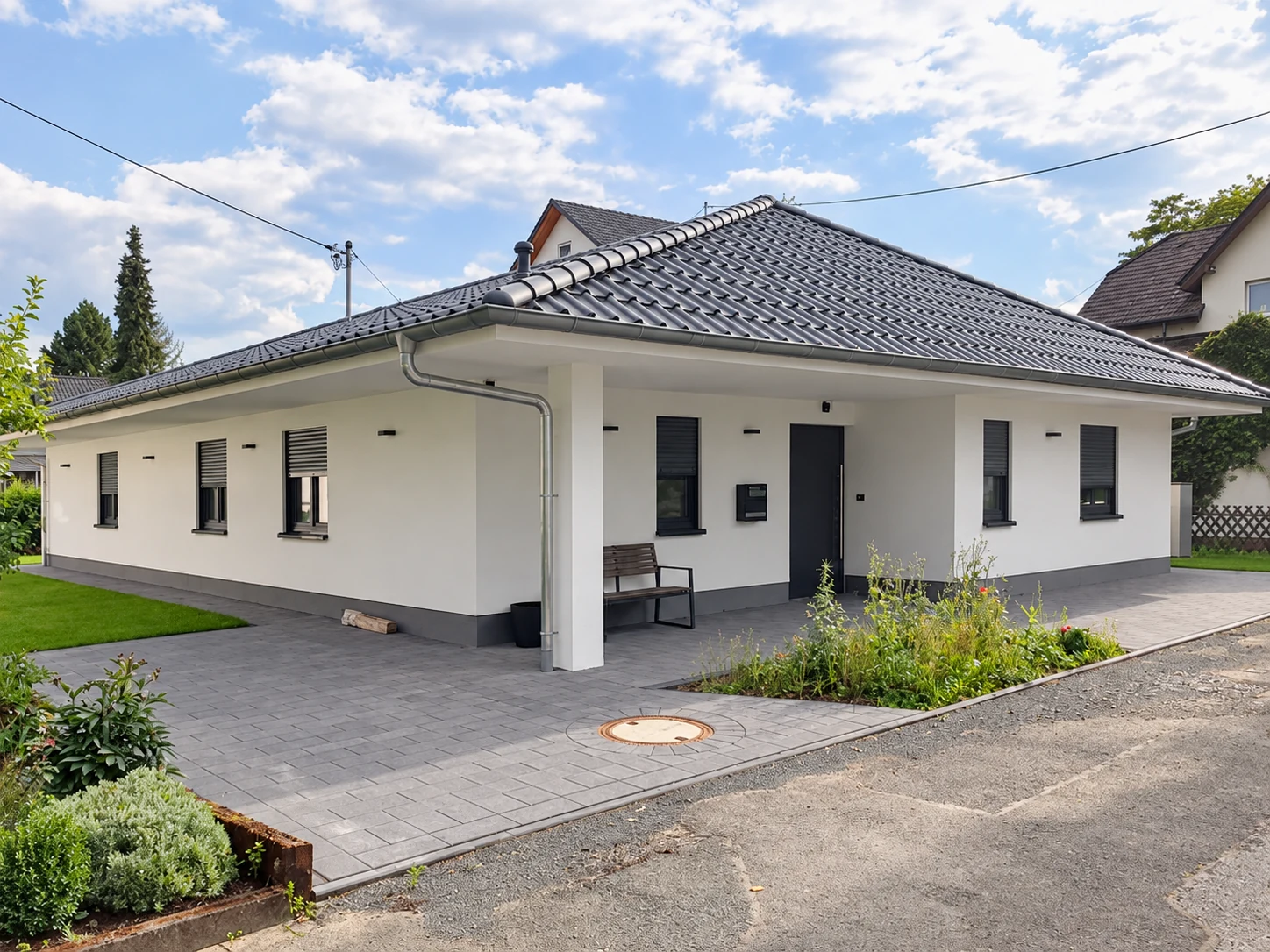 Weiß verputzter Bungalow mit dunklem Sockel