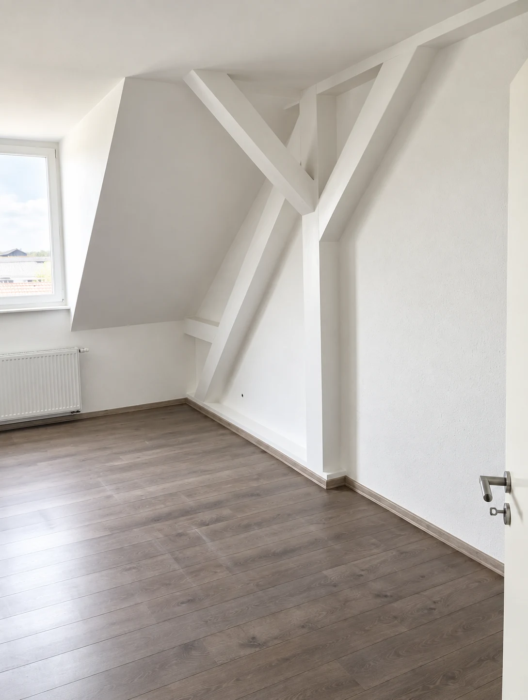 Dachgeschoss mit weißen Balken und dunklem Boden